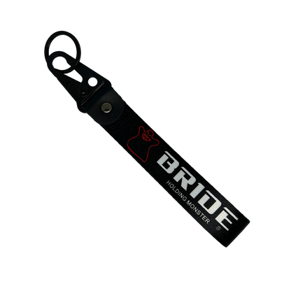 Black key tag with BRIDE HOLDING MONSTER branding in white print – Motorev embroidered car keychain
