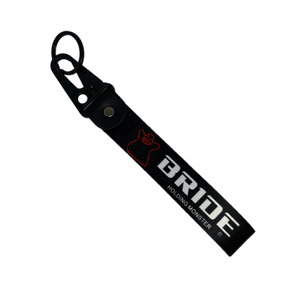 Black key tag with BRIDE HOLDING MONSTER branding in white print – Motorev embroidered car keychain