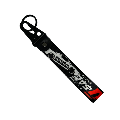 Motorev Initial D AE86 Trueno car key tag, a black wrist strap JDM keyring featuring the iconic Toyota AE86 Trueno silhouette with Japanese kanji and Initial D branding, built for JDM and anime car culture enthusiasts UK